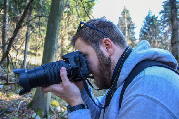一个男人在树林里拍摄大自然的花朵图片下载