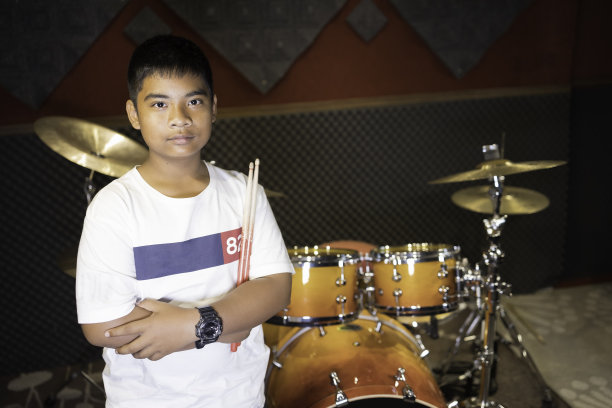 一个亚洲男孩的肖像与鼓在音乐练习室图片下载