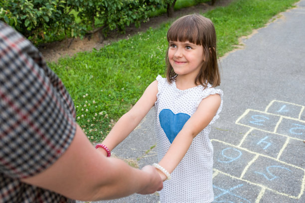 快乐的女孩牵着妈妈的手在一个夏天的户外特写。图片下载