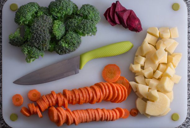 白色的桌子上，刀旁放着切碎的蔬菜图片下载