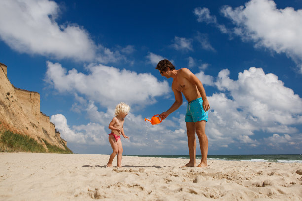 快乐的家庭，爸爸和女儿在夏天的海滩上，在海边放松和玩耍图片下载