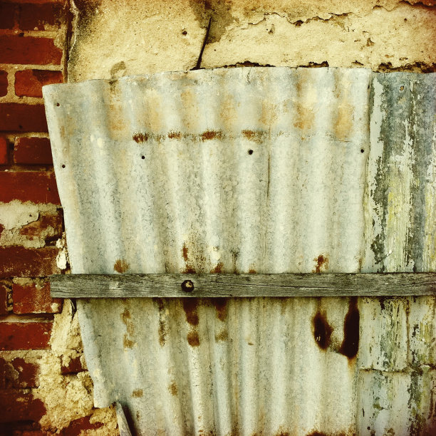 旧的损坏的波纹铁附着在旧石墙上图片下载