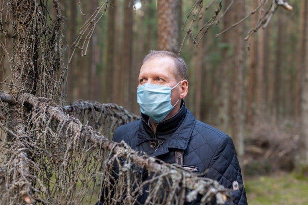 一个戴医用面具的人在森林里。图片下载