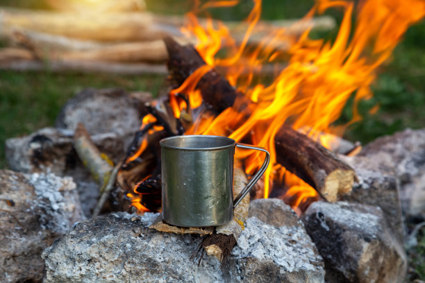 钢杯在自然界的明火上。烹饪着火了。在夏天露营。图片下载
