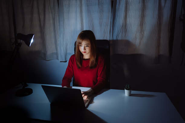 亚洲女性工作到深夜用笔记本电脑在家办公室看屏幕显示器不开心的工作辛苦，自由职业者呆在家里隔离失眠的危机冠状病毒在黑暗的房间。图片下载