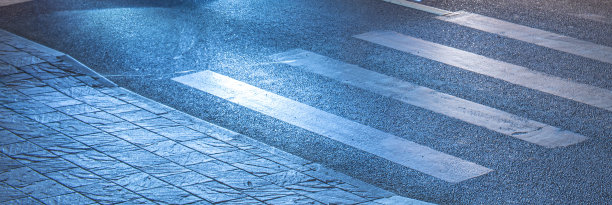 夜间行人过街时遇蓝灯。霓虹灯下潮湿的柏油路上的人行道。运动中的汽车发出的模糊的灯光图片下载