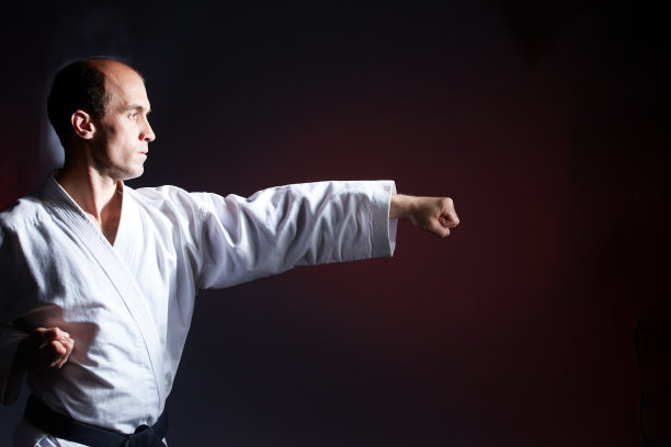 在暗红色的背景下，一个年轻的运动员在表演拳击动作图片下载