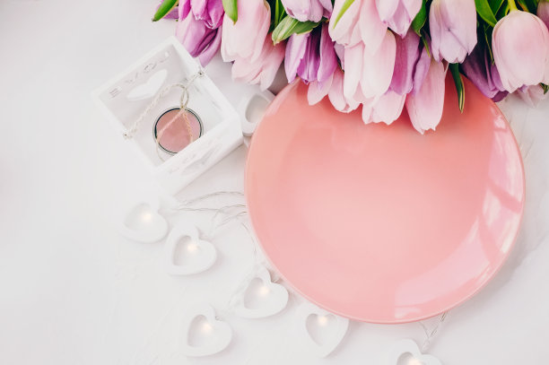 浅背景上有一个心形花环的粉红色盘子。平面位置，俯视图，复制空间。图片下载