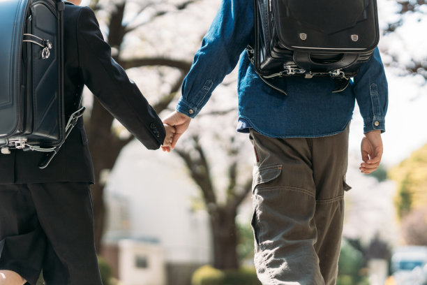 日本小学高年级学生和一年级学生在十字路口举手图片下载