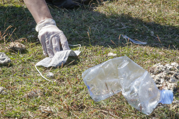 从草地上捡塑料瓶的女人。环保人士收集塑料垃圾的照片。志愿者在户外捡起一次性塑料。图片下载