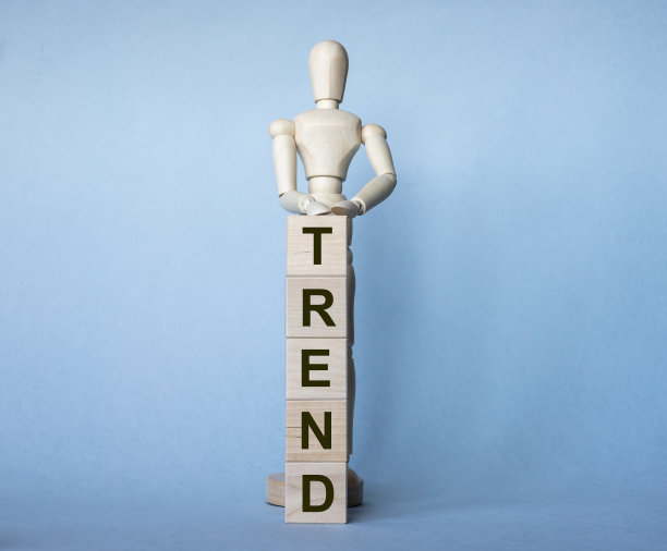 在蓝色背景下，一个木头人握着的立方体上的趋势字。本空间图片下载