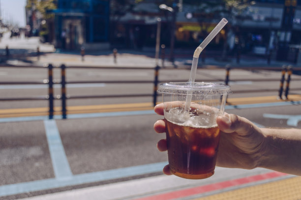 在一个晴朗炎热的日子里，男人手里拿着冰咖啡杯图片下载