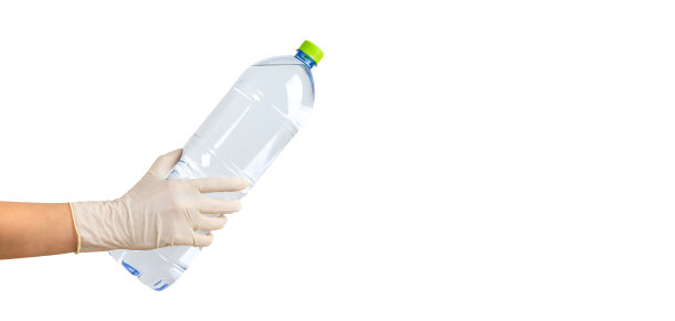 手掌上的塑料瓶水孤立在白色背景上。戴上防护手套。送货上门的理念，在冠状病毒大流行期间安全购物。横幅，模板，文本空间图片下载