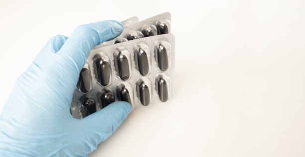 男性的手在一个医疗手套拿着一把黄色药丸。孤立在白色照片上。图片下载