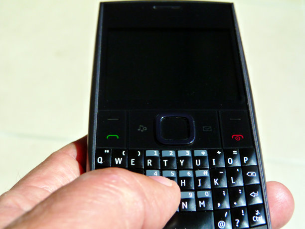 男性拇指打字在老式的黑色手机qwerty键盘上图片下载