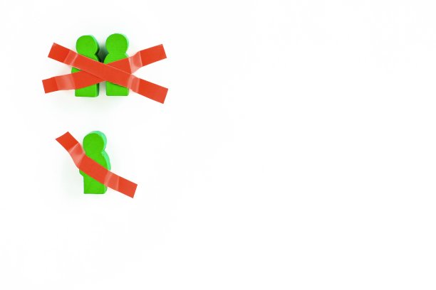 玩具木制的人用胶带粘在白色的墙上。在新冠肺炎大流行期间保持身体隔离、在家、社交距离、隔离、强制隔离、禁闭的概念。图片下载