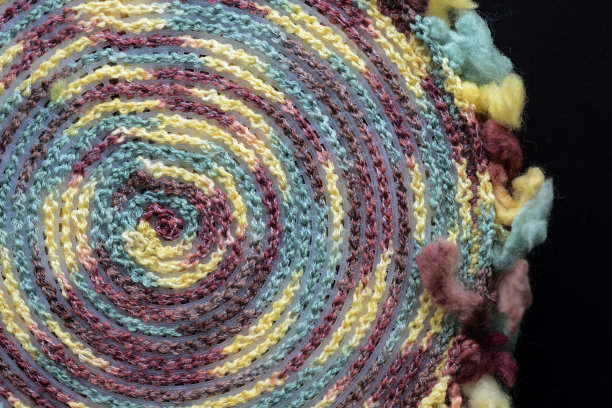 在一个黑色的背景近景上，一个基于塑料帆布的从反面的混合线钩编的圆的碎片图片下载