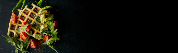 新鲜烘焙的比利时华夫饼配芝麻菜、番茄和牛油果在黑色盘子里。美味的华夫饼。早餐的概念。健康的早餐图片下载