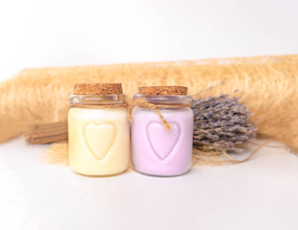 白色背景上放着护肤霜的两个玻璃瓶。从软木塞软木塞。有选择性的重点。软木材料。河岸上画着一颗心。有选择性的重点。水平的照片。背景是薰衣草花和物体制成的木材离焦。手工制作的图片下载