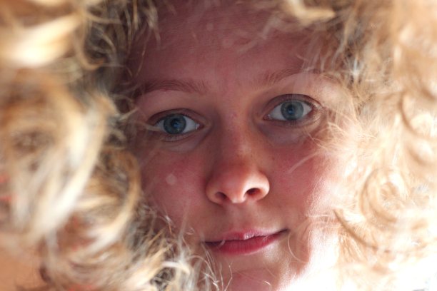 美丽的年轻女孩，她的头发。这个女孩从上到下看，所以她的头发垂下来，只有她的脸可以看到。女孩的眼睛睁得大大的，嘴角挂着微笑。图片下载