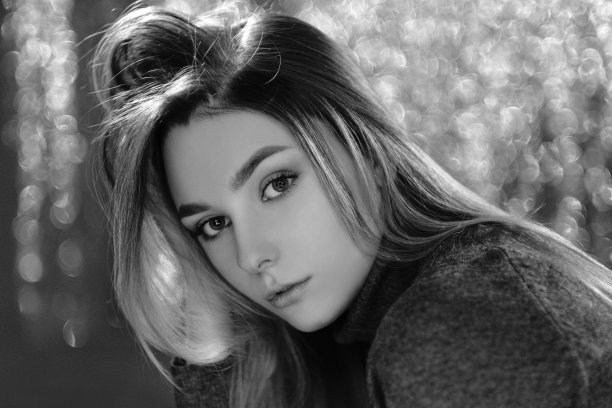 戏剧性的黑白肖像，一个美丽的女孩在黑暗的背景在工作室拍摄模糊的背景图片下载