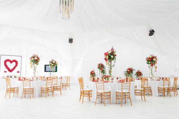 美丽的宴会厅下有一个帐篷，用于举行婚宴。一个婚礼帐篷的内部装饰为客人准备。装饰花。红色主题图片下载