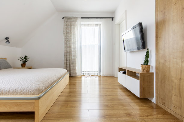 真实的照片，一个明亮宽敞的酒店卧室的室内木床和橱柜，电视在墙上和木地板图片下载