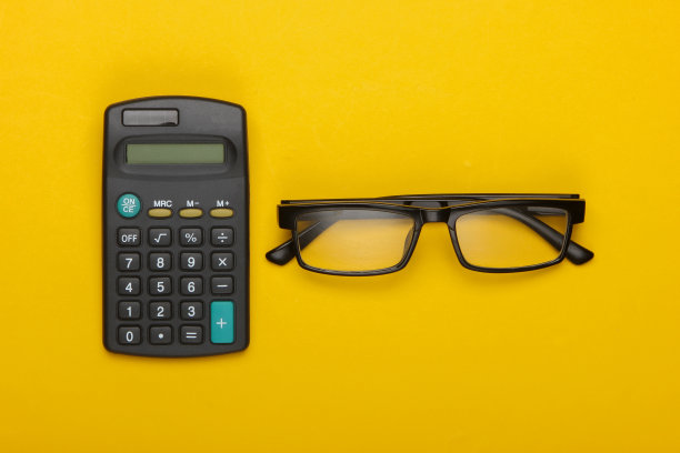黄色背景上的计算器和经典眼镜。经营理念。前视图。平躺图片下载