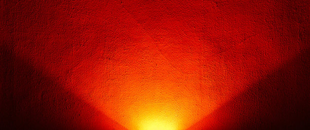 一盏红灯从下面照亮了墙壁。抽象的背景或纹理。图片下载