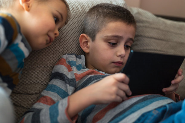 两个孩子在家里的沙发上玩电子产品图片下载