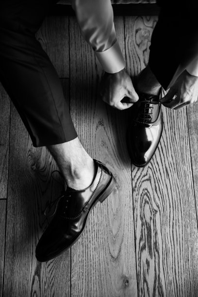 这个男人正在穿鞋。你可以看到系鞋带的手。图片下载