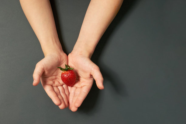 红色多汁的成熟草莓在孩子的手中灰色的背景。副本的空间。图片下载