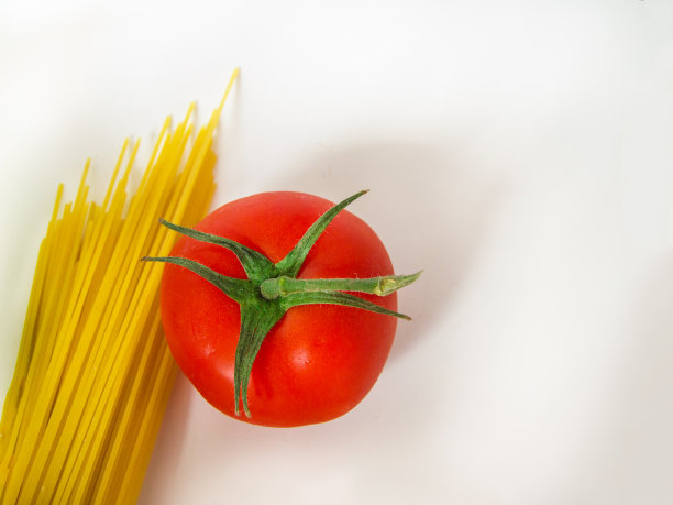 烹饪传统意大利面的原料——生意大利面和番茄，俯视图，白色背景，空间拷贝图片下载