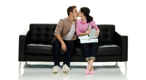 白人丈夫坐在地板前的白色背景穿着纽扣衬衫和持有盒子图片下载