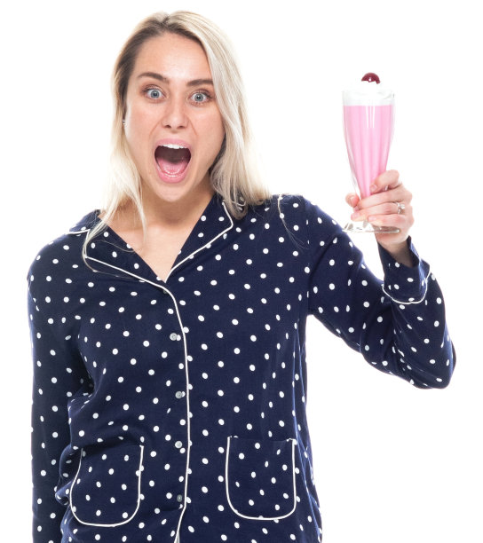 白人年轻女性站在白色背景穿着睡衣和拿着冰沙图片下载