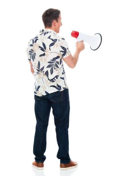 白人年轻男性穿着牛仔裤，手持扩音器站在白色背景前图片下载