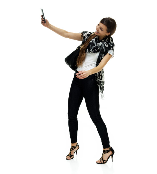 白人女性戴着围巾，用智能手机站在白色背景前拍照图片下载