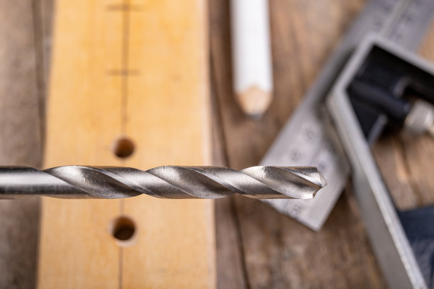 用金属钻头在一块木头上钻孔。家庭作坊里的小木工。光背景。图片下载