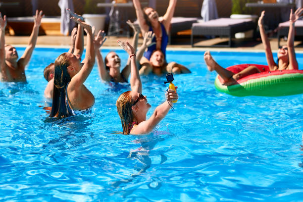 多种族的朋友在私人别墅游泳池聚会。阳光明媚的日子里，在豪华度假胜地，快乐的年轻人穿着泳衣跳舞，玩着充气浮子。比基尼的女孩图片下载