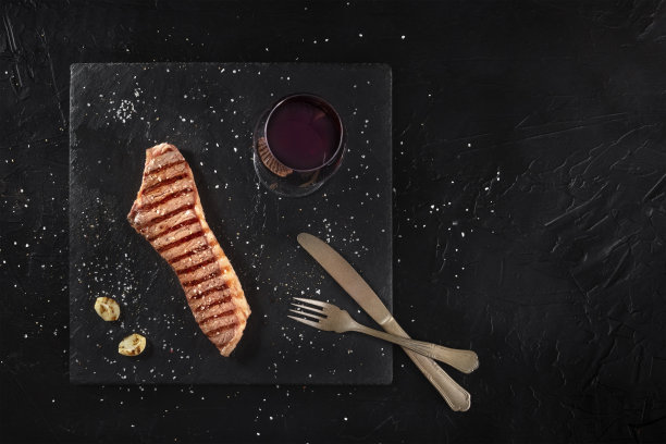 烤牛排与红酒，从顶部拍摄在一个黑暗的背景与复制空间图片下载