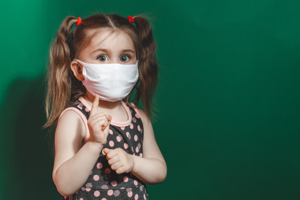 概念照片的小女孩在医疗面具显示指向的手指在绿色背景近距离图片下载