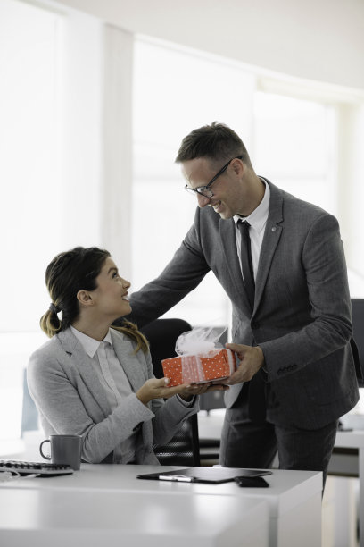 年轻男子在办公室给漂亮的女商人一个惊喜。图片下载