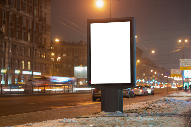 广告牌垂直灯箱在城市的夜晚发光，在街道上靠近道路。图片下载