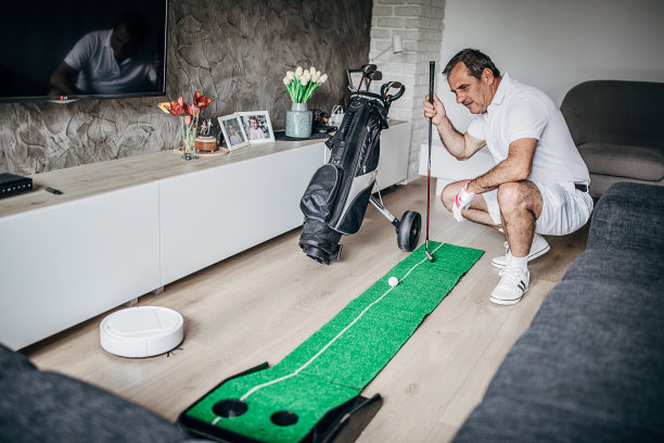 男人在家里的客厅里打迷你高尔夫图片下载