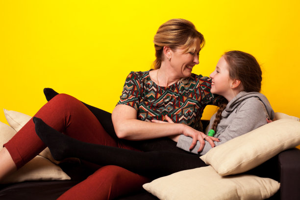 美丽的女孩和wjman躺在黑色的沙发上，穿着自制的衣服和枕头图片下载