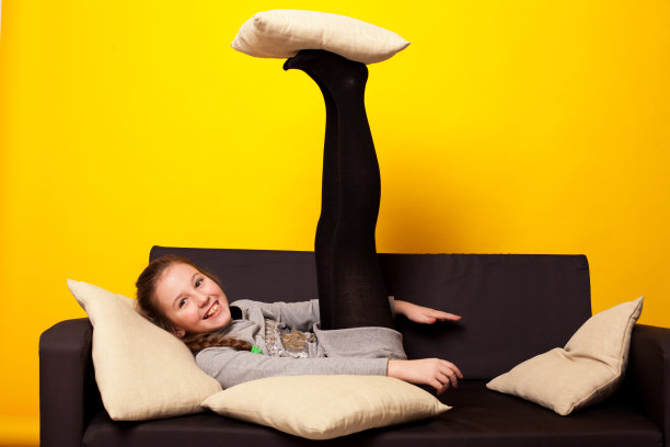 一个漂亮的女孩躺在黑色的沙发上，身上穿着自制的衣服和枕头图片下载