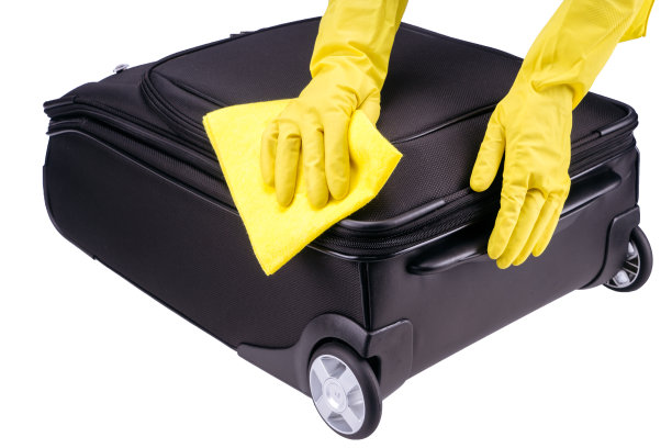 双手在黄色橡胶手套清洁黑色塑料手提箱图片下载