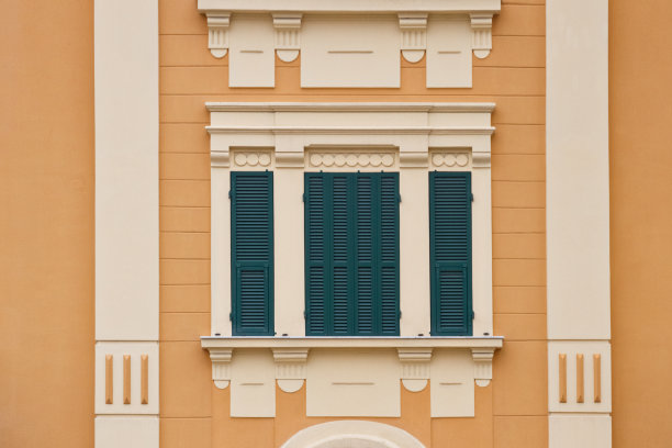 黄色墙壁上的绿色木质窗户，白色框架的百叶窗图片下载