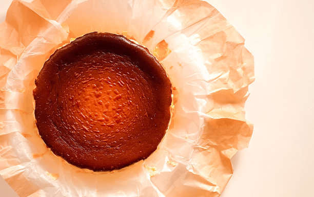 俯视图巴斯克烤乳酪蛋糕在烤纸上的白色背景。图片下载