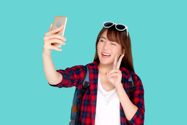 美丽的肖像年轻的亚洲女人开朗的微笑和在智能手机上自拍，美丽的女孩穿旅行夏天享受和乐趣在假期孤立的蓝色背景，假日概念。图片下载